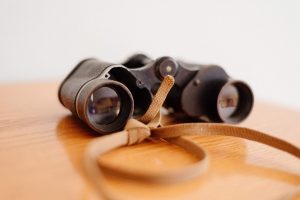 vintage binoculars placed on top of a wooden table services