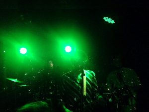 LaGardère live concert at Sabotage, with the vocalist and the drummer playing in a dark greenish setting